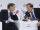 Denis Manturov e outro participante conversando em painel do Fórum Gaidar, com bandeira da Rússia ao fundo.