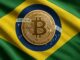 Bandeira do Brasil com uma moeda de Bitcoin dourada no centro do círculo azul, substituindo o brasão tradicional.