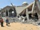Crianças andando perto de prédios destruídos em Gaza após ataques aéreos, mostrando a devastação urbana e o impacto civil do conflito.