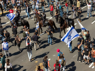 Manifestantes em Tel Aviv bloqueiam uma rodovia durante protestos contra a reforma judicial de Israel, enquanto policiais montados tentam controlar a multidão.