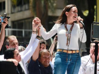 María Corina Machado ergue a mão de apoiadores durante discurso em manifestação política em Caracas, 28 de agosto de 2024.