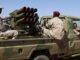 Soldados das Forças de Apoio Rápido (RSF) do Sudão em caminhonete militar equipada com lançadores múltiplos de foguetes no deserto de Darfur.
