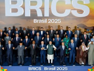 Foto oficial da Cúpula dos BRICS Brasil 2025, mostrando líderes e representantes dos países membros, convidados e organizações internacionais, reunidos em pose oficial e de mãos dadas, com o cenário do pôr do sol e a logo “BRICS Brasil 2025” ao fundo.