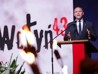 Karol Nawrocki discursando em evento oficial com tochas acesas em primeiro plano e o número 43 destacado ao fundo.