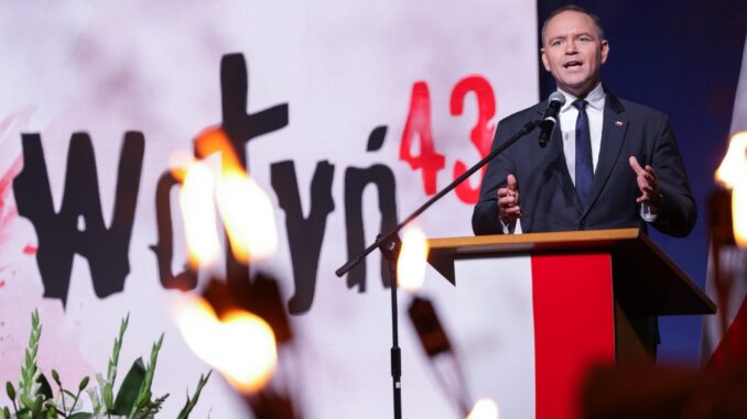 Memória e Justiça: O Discurso de Karol Nawrocki em 11 de Julho de 2025 Karol Nawrocki discursando em evento oficial com tochas acesas em primeiro plano e o número 43 destacado ao fundo.