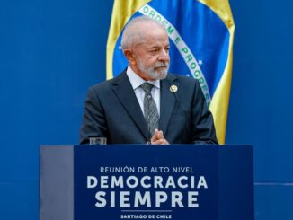 Presidente Luiz Inácio Lula da Silva discursa em reunião internacional de alto nível, com bandeira do Brasil ao fundo.