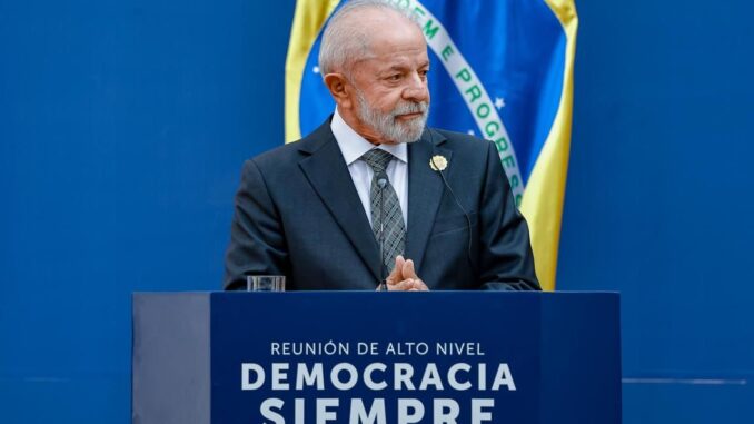 Presidente Luiz Inácio Lula da Silva discursa em reunião internacional de alto nível, com bandeira do Brasil ao fundo.