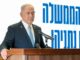 Benjamin Netanyahu em discurso oficial, vestindo terno escuro e gravata azul clara, falando em um púlpito com microfones, com fundo branco e texto em hebraico azul.