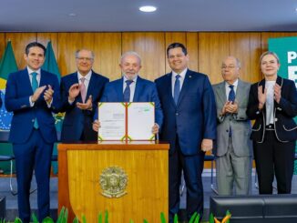 Presidente Lula segura documento do Plano Brasil Soberano, cercado por ministros e autoridades, durante cerimônia oficial.