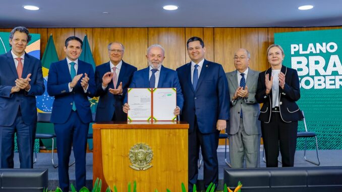 Presidente Lula segura documento do Plano Brasil Soberano, cercado por ministros e autoridades, durante cerimônia oficial.
