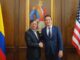 Presidente colombiano Gustavo Petro cumprimenta representante dos EUA em encontro oficial em Bogotá, com bandeiras da Colômbia e dos EUA ao fundo.