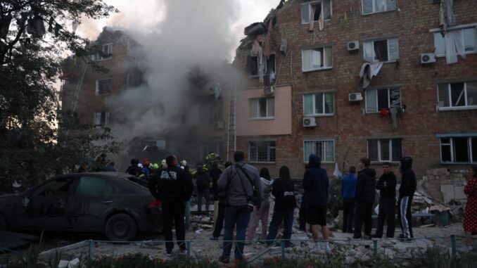 Escombros de Kiev após ataque russo Pessoas observam bombeiros trabalhando enquanto fumaça sai de um prédio residencial danificado em Kiev após ataque com mísseis russos.