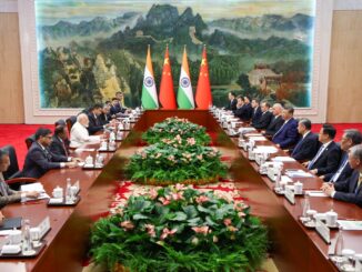 Líderes da Índia e da China em reunião bilateral com suas respectivas delegações, com bandeiras nacionais ao fundo, discutindo cooperação estratégica e relações diplomáticas.