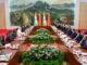 Líderes da Índia e da China em reunião bilateral com suas respectivas delegações, com bandeiras nacionais ao fundo, discutindo cooperação estratégica e relações diplomáticas.