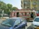Ônibus decorado colorido circulando em rua urbana de Karachi, Paquistão, com carros e edifícios ao fundo.