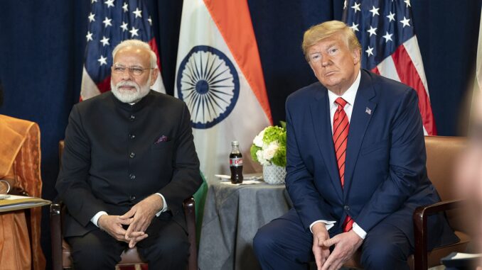 Modi e Trump em Reunião na ONU Primeiro-ministro Narendra Modi e presidente Donald Trump sentados lado a lado em reunião bilateral na sede da ONU, com bandeiras da Índia e dos EUA ao fundo.