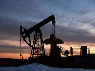Bomba de petróleo operando ao entardecer com céu colorido, simbolizando a indústria petrolífera em contexto de mudanças econômicas globais.