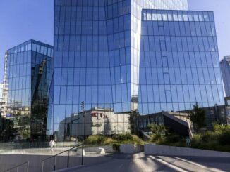 Fachada moderna de um prédio de banco em Vilnius, Lituânia, refletindo o céu e edifícios vizinhos.