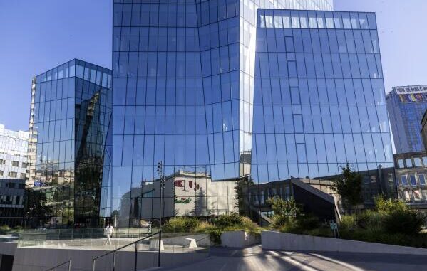 Fachada moderna de um prédio de banco em Vilnius, Lituânia, refletindo o céu e edifícios vizinhos.