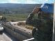 Soldado da ONU da UNIFIL observa a fronteira sul do Líbano usando binóculos, com veículo blindado da ONU ao fundo.