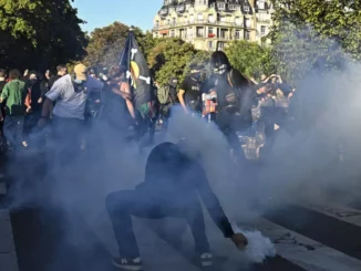 Manifestante tentando pegar uma bomba de gás lacrimogêneo durante protesto em Paris, França, em 18 de setembro de 2025.