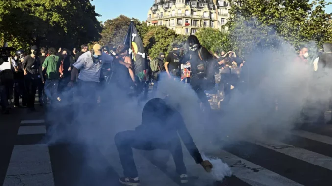 Manifestante tentando pegar uma bomba de gás lacrimogêneo durante protesto em Paris, França, em 18 de setembro de 2025.
