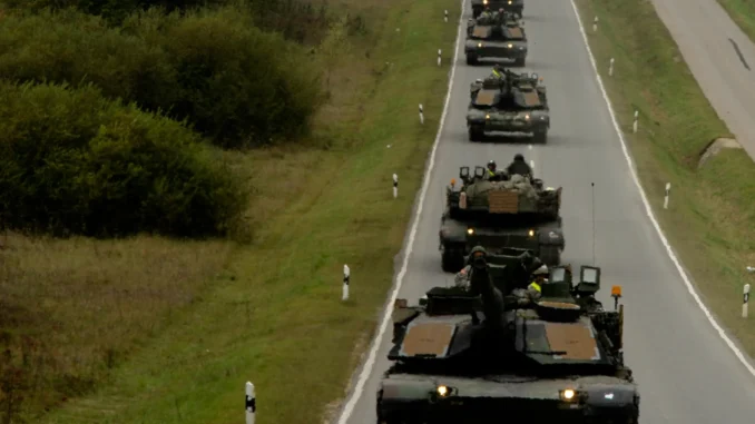 Comboio militar em movimento pela Europa Tanques e veículos militares em comboio deslocando-se por estrada europeia