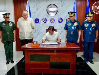 O presidente das Filipinas, Ferdinand R. Marcos Jr., assina documento enquanto é observado por oficiais da Força Aérea e do Exército das Filipinas durante cerimônia de homenagem à Força Aérea do país.