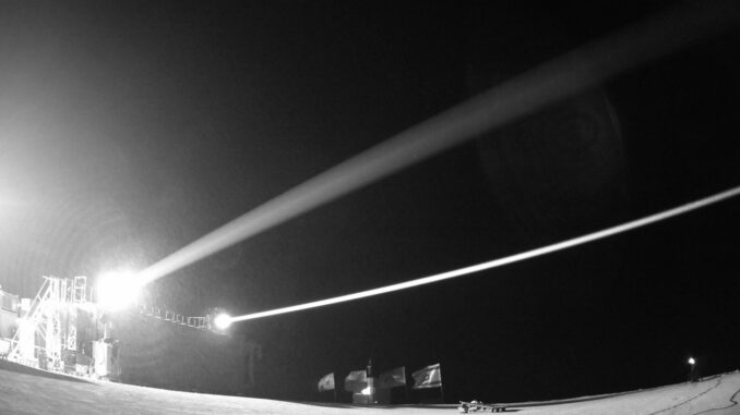 Foto do sistema de defesa a laser Iron Beam da Rafael, em operação noturna, disparando feixes de energia contra alvos simulados.