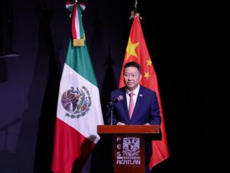 Representante da China discursando em frente às bandeiras do México e da China em evento oficial.