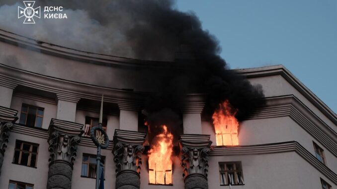 Prédio do governo de Kiev em chamas durante ataque aéreo russo, com fumaça negra saindo das janelas.