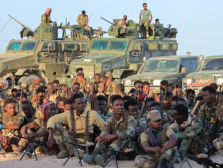 Soldados das Forças Armadas Nacionais Somalis posando em grupo na frente de veículos militares, durante cerimônia de homenagem após vitória contra o Al-Shabaab.