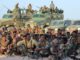 Soldados das Forças Armadas Nacionais Somalis posando em grupo na frente de veículos militares, durante cerimônia de homenagem após vitória contra o Al-Shabaab.