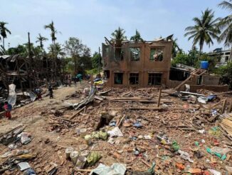 Escola destruída em Thayet Thapin, estado de Rakhine, Mianmar, após ataque aéreo da junta militar, com destroços espalhados e poucas pessoas no local.