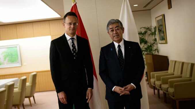 Ministro japonês Takeshi Iwaya com o Ministro das Relações Exteriores da Hungria em reunião oficial, com bandeiras do Japão e Hungria ao fundo.