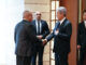 Ministro japonês Takeshi Iwaya cumprimenta representante diplomático durante encontro oficial, enquanto assessores observam ao fundo.