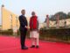 “Primeiro-ministro indiano Narendra Modi e presidente francês Emmanuel Macron apertando mãos em frente a instrumentos astronômicos históricos em Jaipur, Índia.