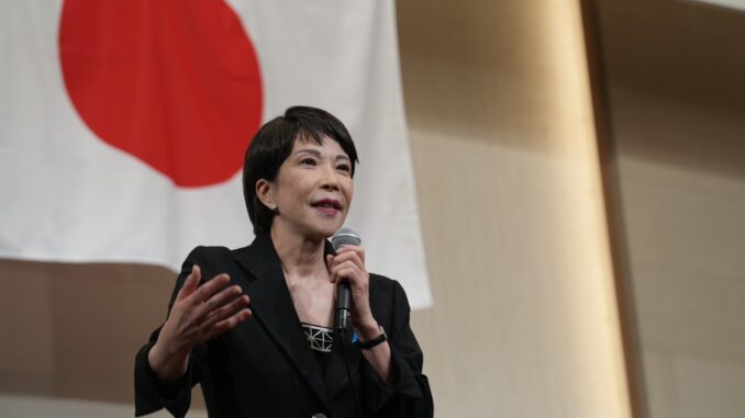 Sanae Takaichi discursando durante palestra na província de Fukuoka, Japão, em 25 de agosto de 2025, com público presente e representantes do LDP.