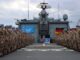 Soldados da Bundeswehr em uniforme de camuflagem alinhados no convés de um navio, com bandeiras da Alemanha e da ONU ao fundo, participando de missão da Força-Tarefa Marítima UNIFIL no Líbano.