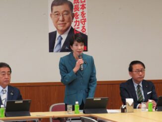 Sanae Takaichi falando em reunião do Grupo de Estudos de Segurança Pública, Terrorismo e Combate ao Crime Cibernético do PLD, com membros do partido e laptops à mesa.