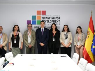 Pedro Sánchez posa com delegados em conferência internacional de financiamento para desenvolvimento, com bandeiras da Espanha e da União Europeia ao fundo.