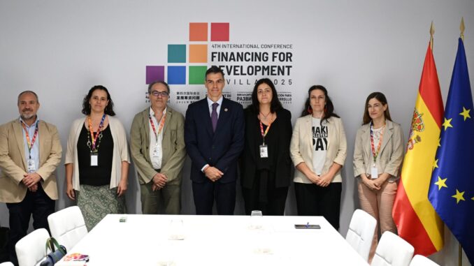 Pedro Sánchez na Conferência Internacional de Desenvolvimento 2025 Pedro Sánchez posa com delegados em conferência internacional de financiamento para desenvolvimento, com bandeiras da Espanha e da União Europeia ao fundo.
