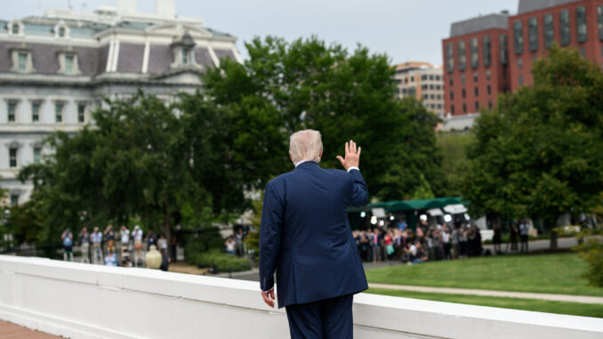 Trump acena para jornalistas em Washington Presidente Donald Trump de costas, acenando para um grupo de jornalistas em frente a prédios governamentais em Washington, EUA.