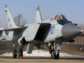 Caça russo Mikoyan-Gurevich MiG-31 estacionado no solo com trem de pouso visível, asas abertas e cabine ocupada pelo piloto.