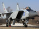 Caça russo Mikoyan-Gurevich MiG-31 estacionado no solo com trem de pouso visível, asas abertas e cabine ocupada pelo piloto.
