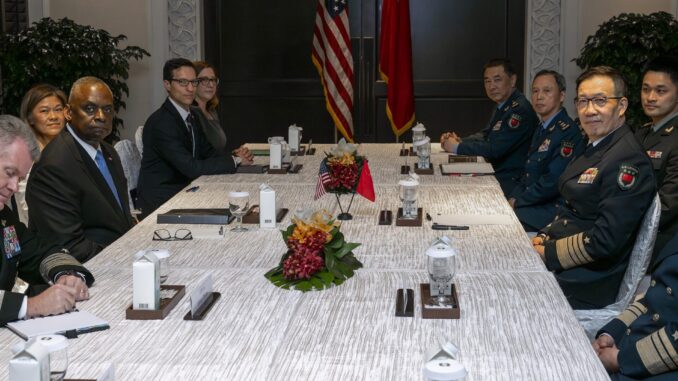 China e EUA mantêm diálogo militar estratégico em Singapura Reunião bilateral entre o Secretário de Defesa dos EUA, Lloyd J. Austin III, e o Ministro da Defesa da China, Almirante Dong Jun, em Singapura, com representantes militares de ambos os países sentados à mesa.
