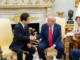 Presidente dos EUA, Donald Trump, e presidente da Coreia do Sul, Lee Jae-myung, apertam as mãos durante reunião na Casa Branca, com assessora ao fundo tomando notas.